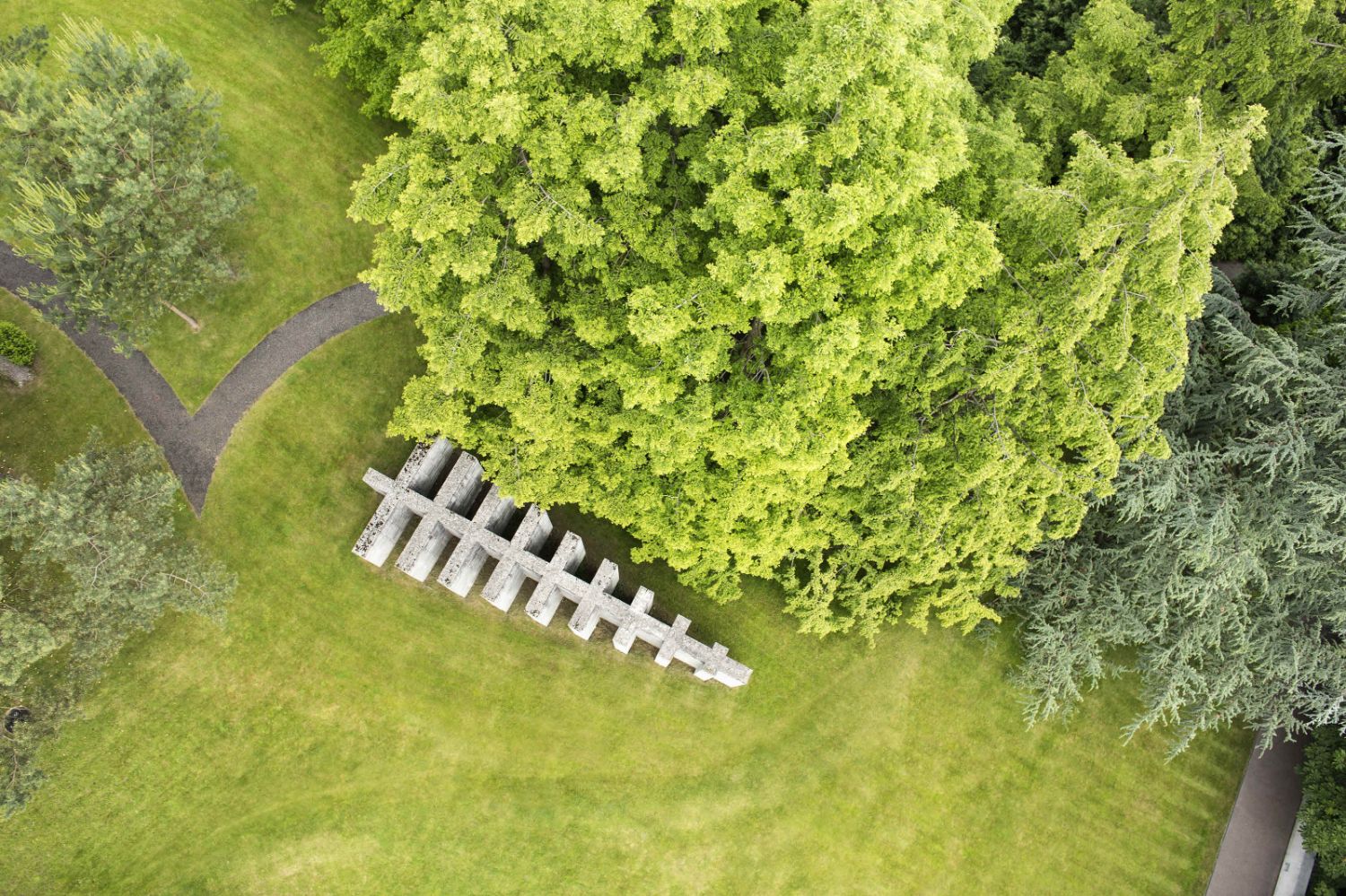 Bird's eye view of a concrete sculpture among green grass and trees.